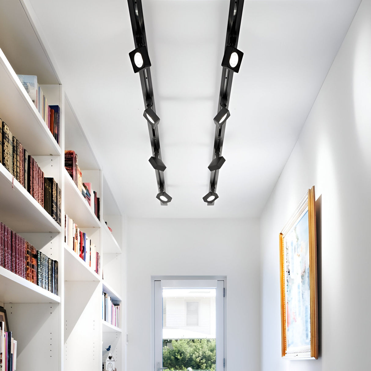 A modern hallway with white walls and a light wooden floor is decorated with bookshelves filled with books on the left and a framed picture on the right wall. The ceiling is enhanced by integrated LED technology featuring the Helionis LED Track Square Spotlight 22W 3000K in black, while a window at the end provides a view of greenery outside.