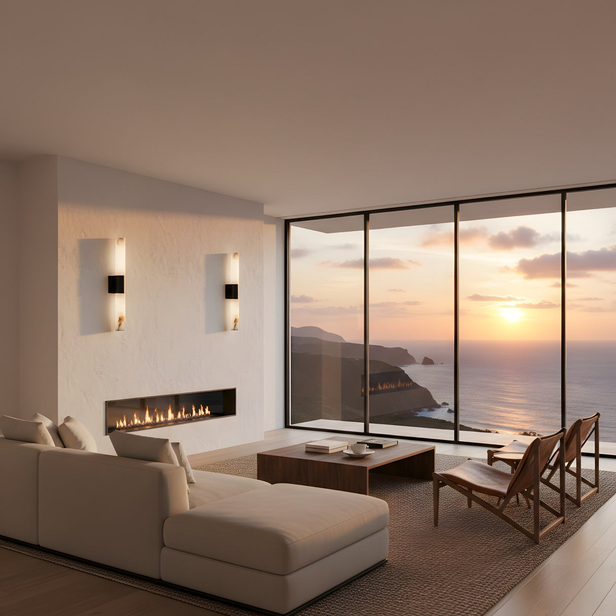 A modern living room with a white sectional, wooden chairs, and a minimalist fireplace showcases the Fiora LED Alabaster Wall Light – Matte Black & Soft White. Floor-to-ceiling windows offer sunset ocean views as warm light fills the serene space.