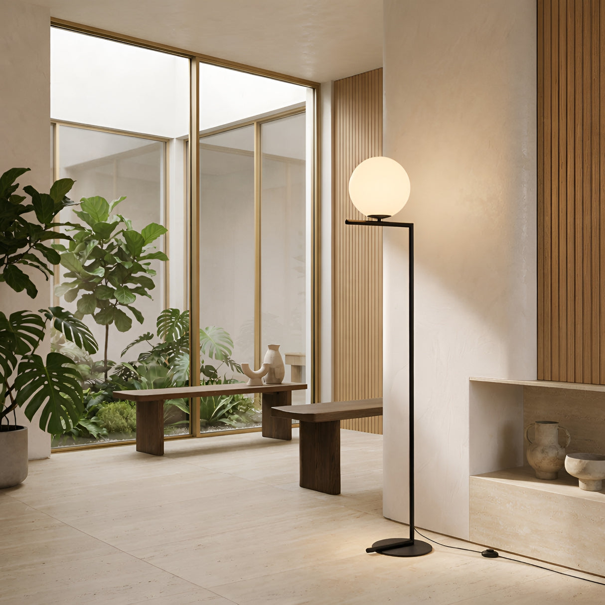 A modern, minimalist living space features large windows, indoor plants, wooden benches, and the Vetra 1 Light Opal Glass Floor Lamp - Black. Light wood and neutral tones create a calm atmosphere enhanced by contemporary lighting.