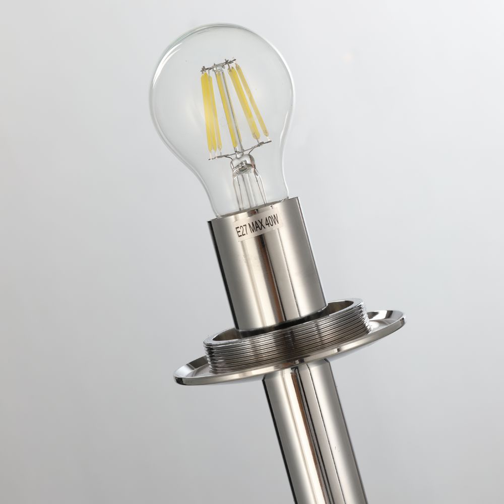 A close-up of a modern LED bulb with visible filaments, mounted on a sleek silver metallic socket, resembles the organic design of the Lava Floor Lamp - Silver. The elegant fixture creates flowing effects, and the engraved socket shines against a soft gray backdrop.