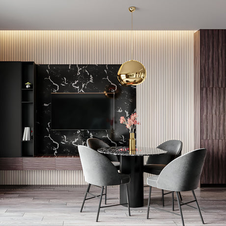 Modern dining area with a round black marble table, four gray upholstered chairs, a gold Lava Small LED Pendant Light with adjustable cable, and a wall-mounted TV on a black marble accent wall with wood paneling and ambient lighting.