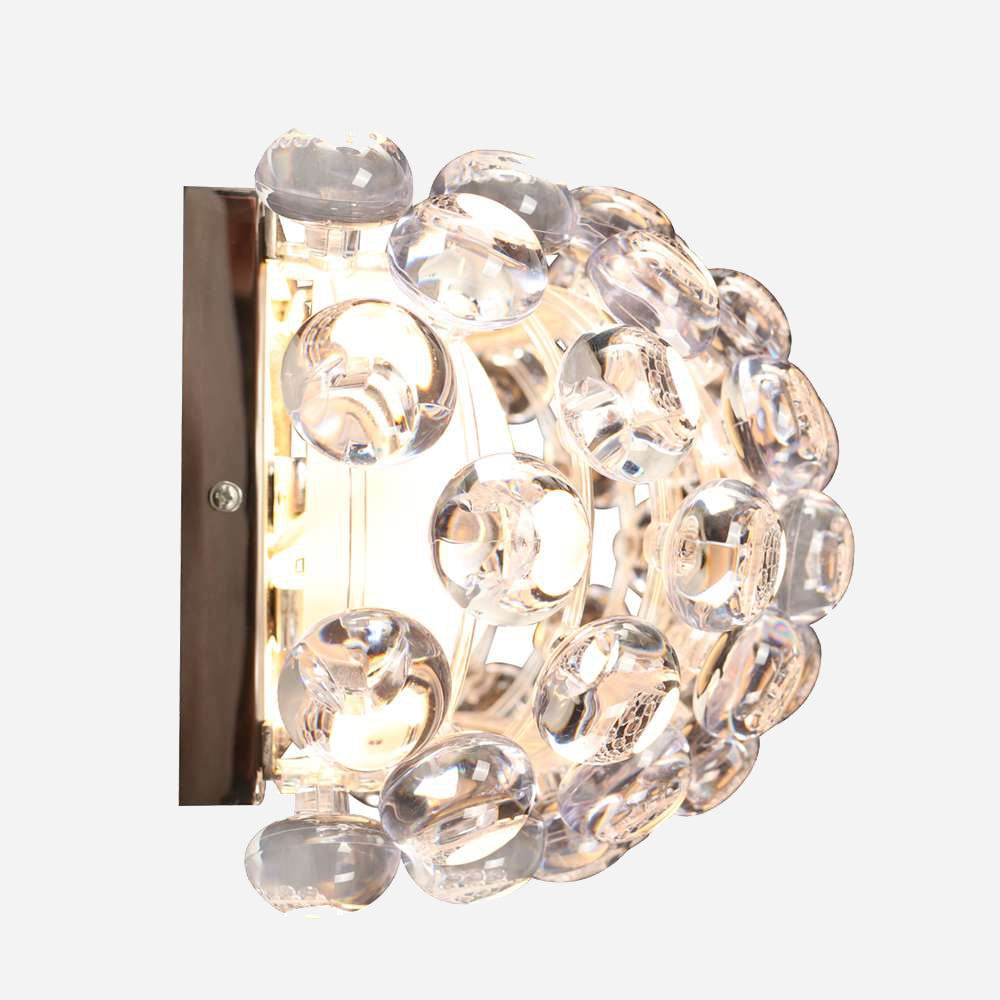 Close-up of the Briller LED Small Wall Light - Transparent, showcasing its metal base and decorative glass bubble design. The light illuminates through the transparent bubbles, creating an elegant and contemporary look ideal for any modern lighting scheme.