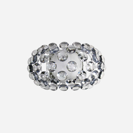 A decorative round ceiling light fixture featuring a mosaic of clear glass beads or crystals offers a sparkling effect, epitomizing modern lighting. This design perfectly complements any arrangement with the Briller LED Small Wall Light - Transparent, especially against a white background.