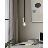 Pendant light with a brushed metal lamp holder suspending a clear glass E14 golf ball LED bulb with visible filament strips, shown glowing warm white above a desk.