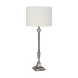 Canterbury table lamp with a candlestick-style antique silver aluminium base, square stepped foot, and white drum shade, shown on a plain white background.