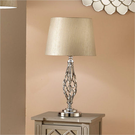 Jenna Silver Metal Twist Detail Table Lamp with a tapered fabric shade and spiral chrome base, shown on a bedside cabinet against a soft pink wall.