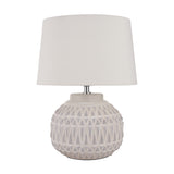 Anneli table lamp with a round ceramic base in warm white featuring an Aztec textured pattern, topped with a white tapered fabric shade, on a plain background.