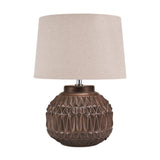 Anneli table lamp with a round bronze ceramic base featuring geometric Aztec texture, paired with a tapered linen shade, shown on a plain white background.