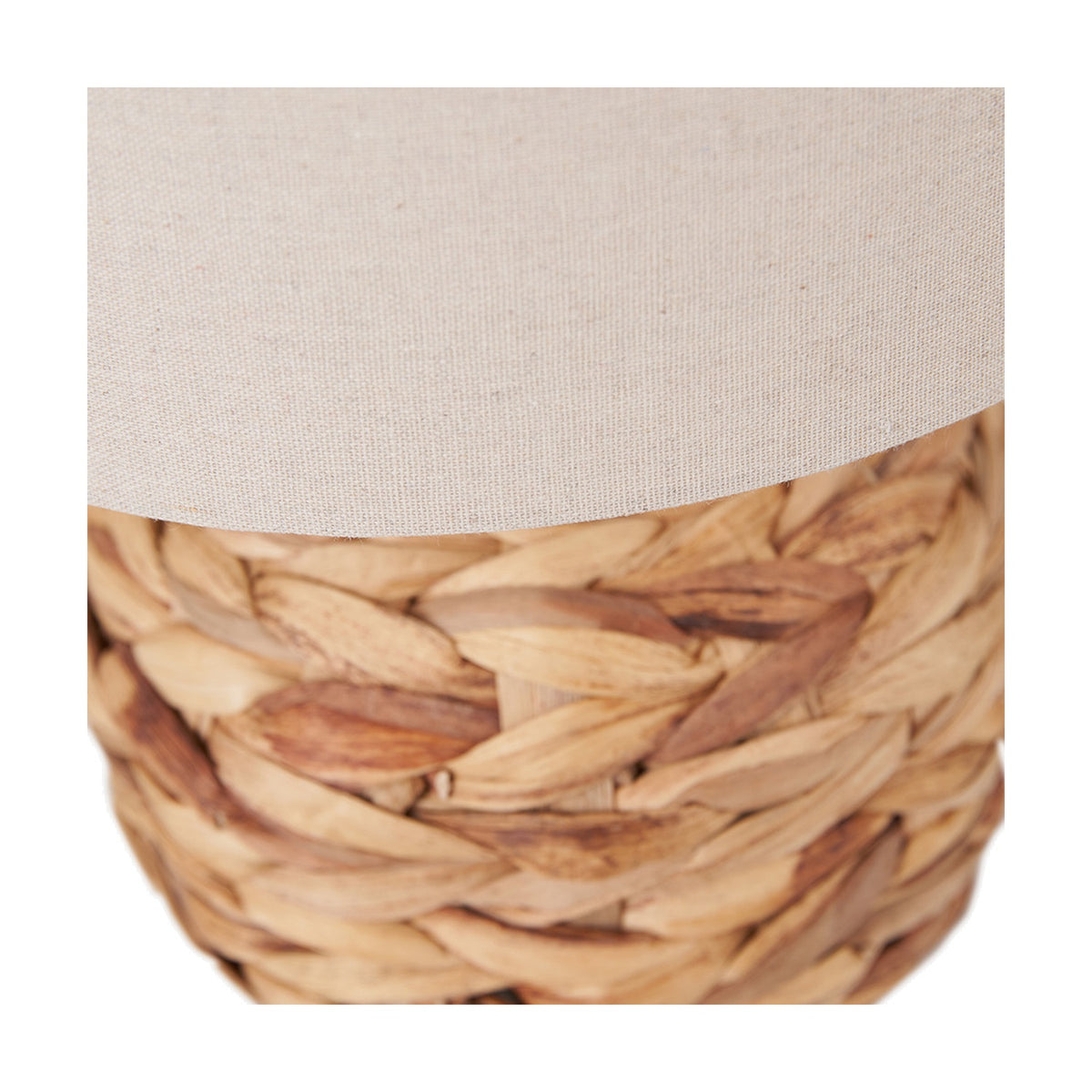 Close-up of the Zadi Table Lamp's natural plaited water hyacinth base beneath a plain oatmeal fabric shade, showing the woven texture in detail.