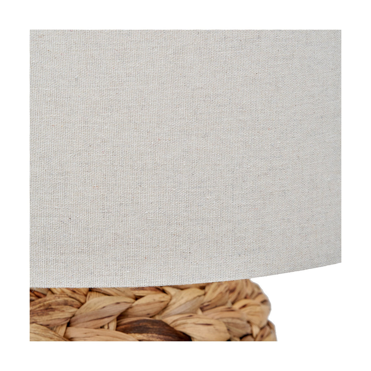 Close-up of the Zadi Natural Plaited Tall Water Hyacinth Table Lamp, showing the woven natural wicker base and plain light grey fabric drum shade.