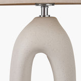 Close-up of the Laila Natural Beige Organic Tall Ceramic Table Lamp base, showing speckled beige ceramic with an arched cut-out and chrome fitting beneath a linen shade.