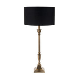 Canterbury Antique Brass Table Lamp with black drum shade, tall fluted metal stem and square stepped base, shown on a plain white background.