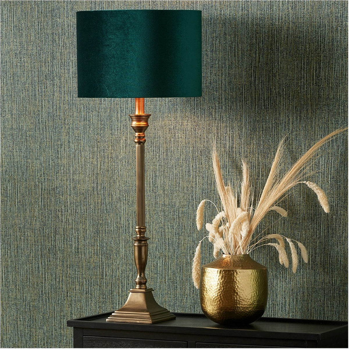 Canterbury Antique Brass Table Lamp Base with turned column stem and stepped square foot, styled with a teal shade on a dark sideboard beside a hammered gold vase.