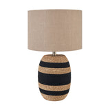 Kalutara Tall Table Lamp with woven sea grass base in black and natural stripes, brass-tone neck, and drum-shaped natural linen shade on a plain white background.