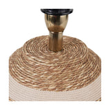Close-up of the Talalla table lamp base showing woven natural sea grass coiling around a brushed brass stem, with beige braided rope trim on the base.