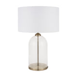 Cloche table lamp with a clear glass dome base, slim antique brass stem, and white drum fabric shade, shown on a plain white background.