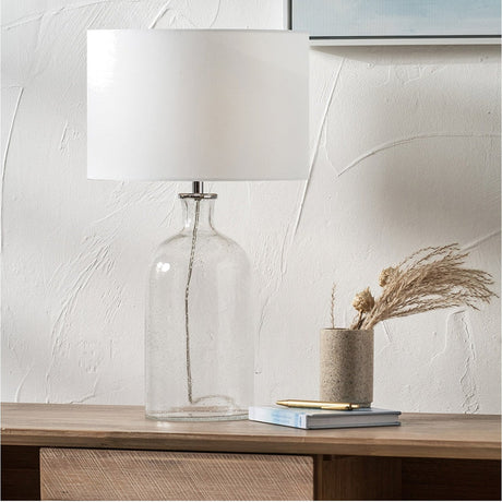 Bellamy Clear Bubble Glass Table Lamp, 53cm, with a white drum shade on a chrome fitting, styled on a wooden sideboard beside a vase and books.