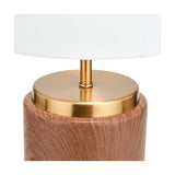 Close-up of the Carrara Wood Effect Ceramic Table Lamp base, showing a brushed brass neck and cap atop a wood-effect ceramic cylinder base, with a white fabric shade above, on a plain background.