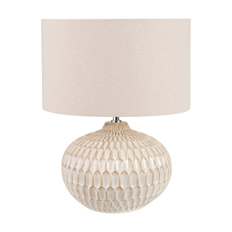 Cassius table lamp with a rounded warm white ceramic base featuring a textured honeycomb pattern, topped with a cylindrical linen drum shade, shown on a plain white background.