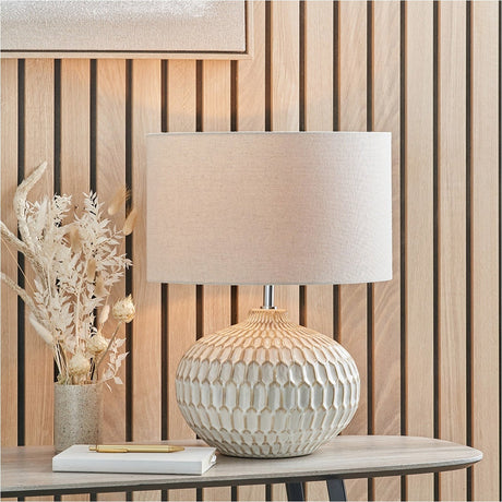 Cassius Warm White Textured Glazed Ceramic Table Lamp, 48cm, with honeycomb-textured base and linen drum shade, styled on a console table beside dried florals and a wood-slat wall.