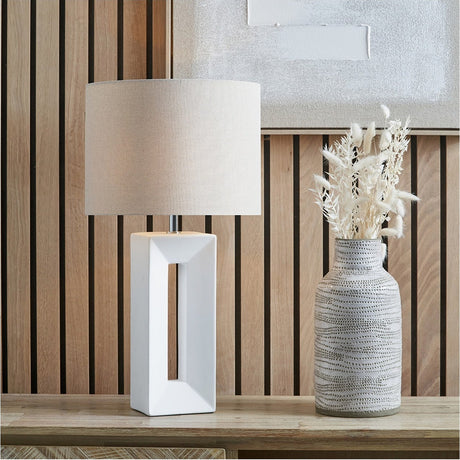 Block White Ceramic Tall Table Lamp, 58cm, with a rectangular open-front ceramic base and linen drum shade, shown on a wooden sideboard beside a dried floral vase.