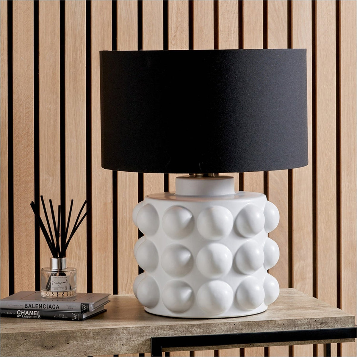 Serenity White Bobbled Ceramic Large Table Lamp Base with black drum shade, styled on a wooden console table against a slatted wood panel wall.