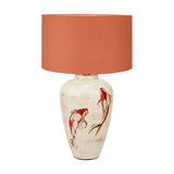 Emerayn Koi ceramic table lamp with a cream base hand-painted with red and white koi fish, paired with a terracotta drum shade on a plain white background.
