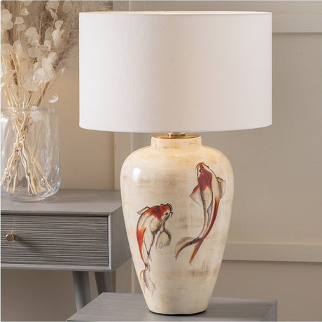Emerayn Koi Ceramic Table Lamp Base, 46cm, with hand-painted koi fish design in red and cream tones and a white drum shade, shown on a grey side table.