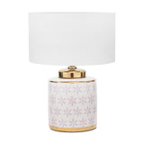 Thea table lamp with a white drum shade on a ceramic base featuring a lilac floral pattern and gold accents, shown on a plain white background.