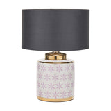 Table lamp with a white ceramic base featuring lilac floral pattern and gold trim, paired with a charcoal drum shade, on a plain white background.