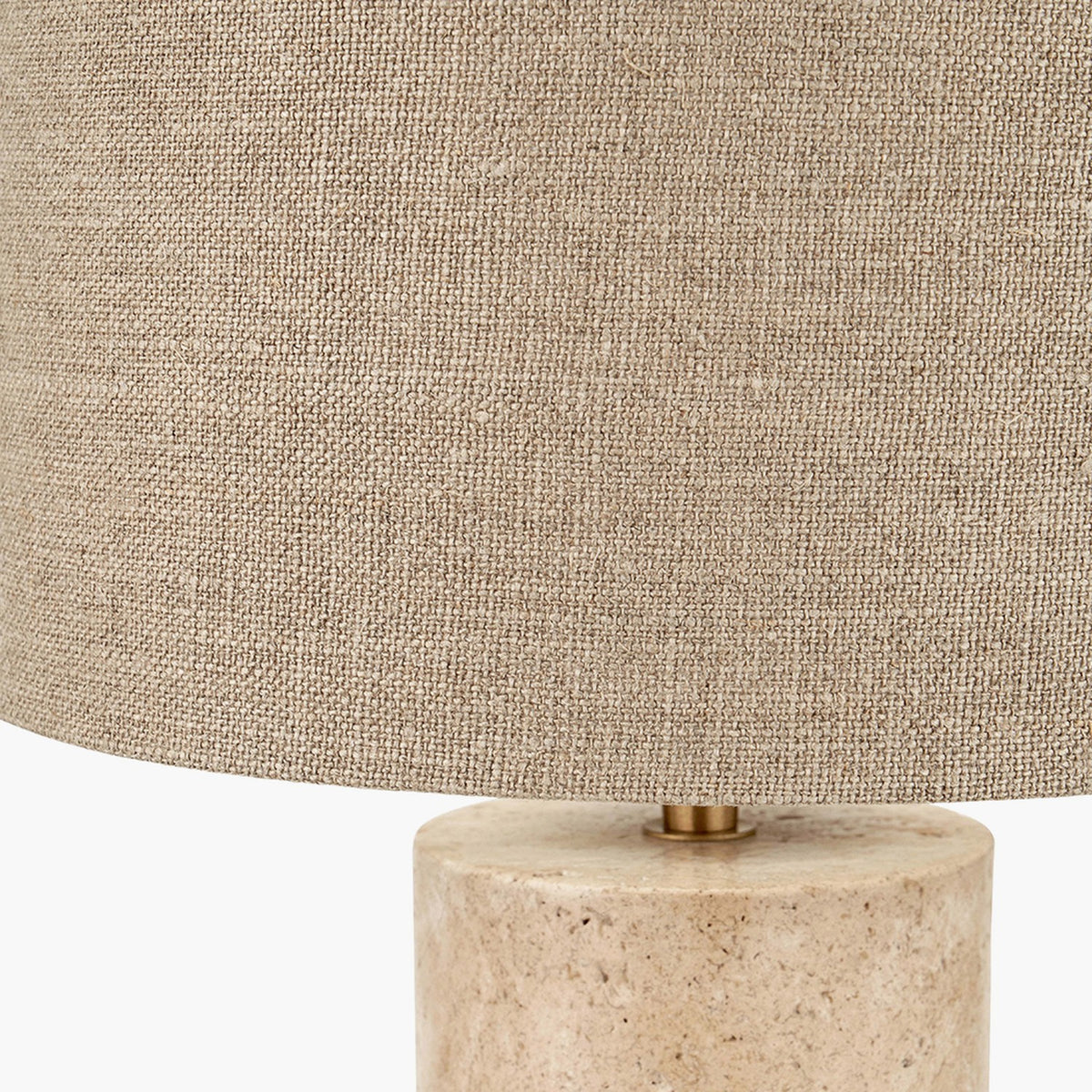 Close-up of the Kanoa Limestone Cylinder Table Lamp, showing a textured linen drum shade with brass fitting atop a natural stone cylindrical base.