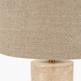 Close-up of the Kanoa Limestone Cylinder Table Lamp, showing a textured linen drum shade with brass fitting atop a natural stone cylindrical base.
