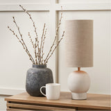 Althea Sandstone Table Lamp, 48cm, with round stone base and natural linen drum shade, styled on a wooden sideboard beside a stoneware vase and marble mug.