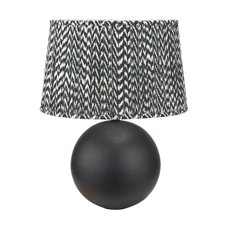 Benio table lamp with a matt black spherical metal base and a black and white chevron patterned fabric drum shade, shown on a plain white background.