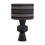Koa Black Mango table lamp with a sculptural sectioned wood base and a black and white patterned drum shade, shown on a plain white background.