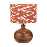 Kiah table lamp with round oiled mango wood base in brown, paired with a red and white ikat-patterned drum shade, on a plain white background.
