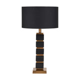 Maximo table lamp with a stacked cube base in matt black and antique brass, paired with a black drum shade, shown on a plain white background.
