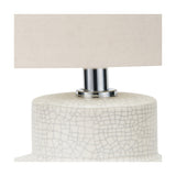 Close-up of the Elure White Crackle Effect Table Lamp's ceramic base with fine crackle glaze, chrome neck fitting, and beige rectangular shade against a plain white background.