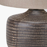 Close-up of the Kai Earth Brown Textured Ceramic Table Lamp base, showing a dashed cream pattern on brown ceramic beneath a beige linen drum shade.