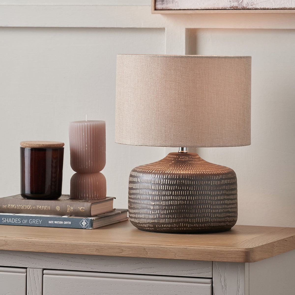 Kai Earth Brown Textured Ceramic Table Lamp, 34cm, with beige drum shade on a ridged brown ceramic base, styled on a wooden sideboard beside books and candles.