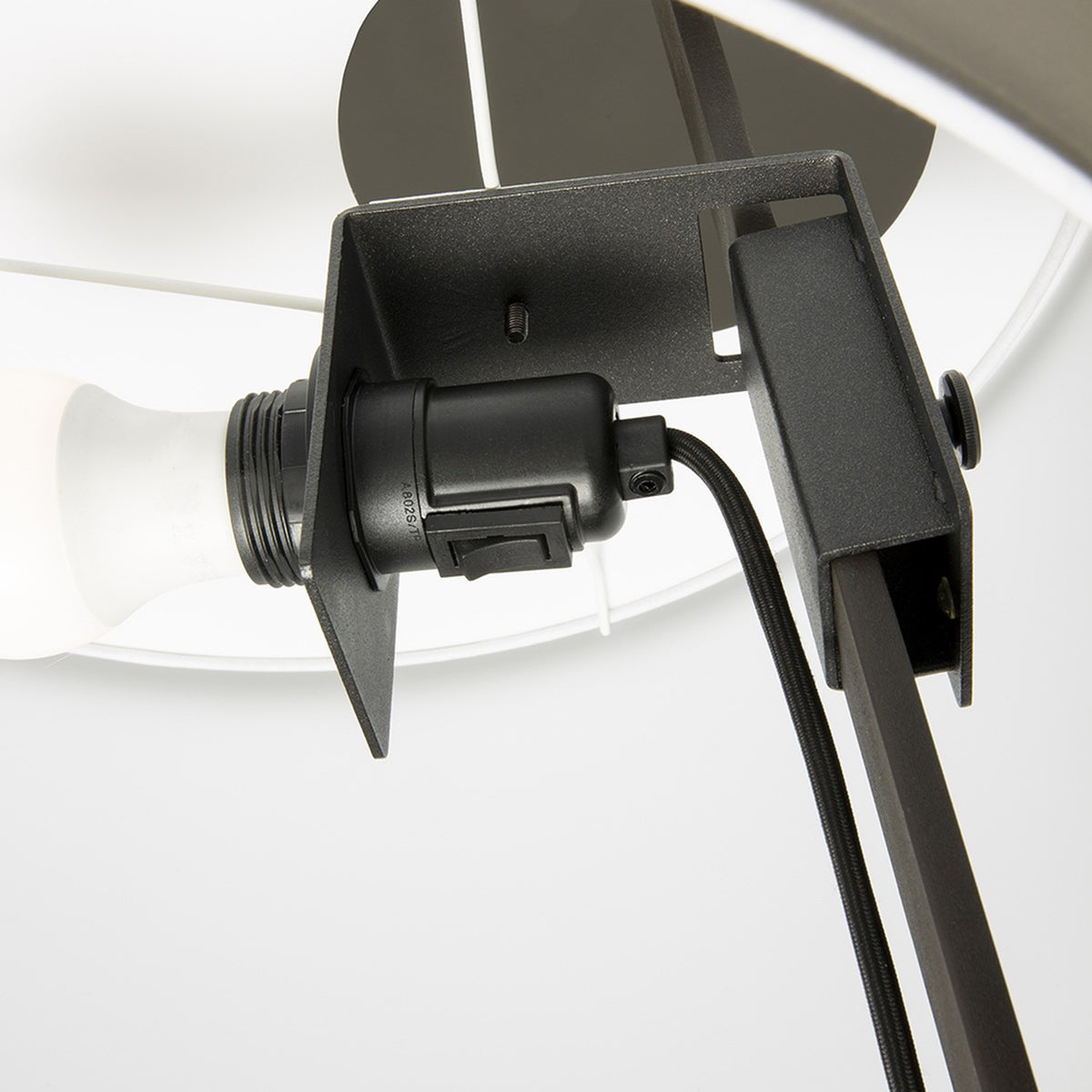 Close-up of the Gilvorne floor lamp's E27 bulb holder and anthracite iron bracket fitting inside the white cotton drum shade, showing wiring and mounting arm.