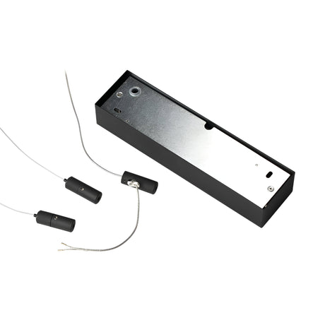 A black rectangular electronic device with three attached cylindrical components on wires evokes the Arcena Round LED Suspension Light - Dimmable, 3000K, Black, 70cm. The primary unit features a metallic surface with visible screws and openings, suggesting that the wires likely connect to dimmable lighting elements.