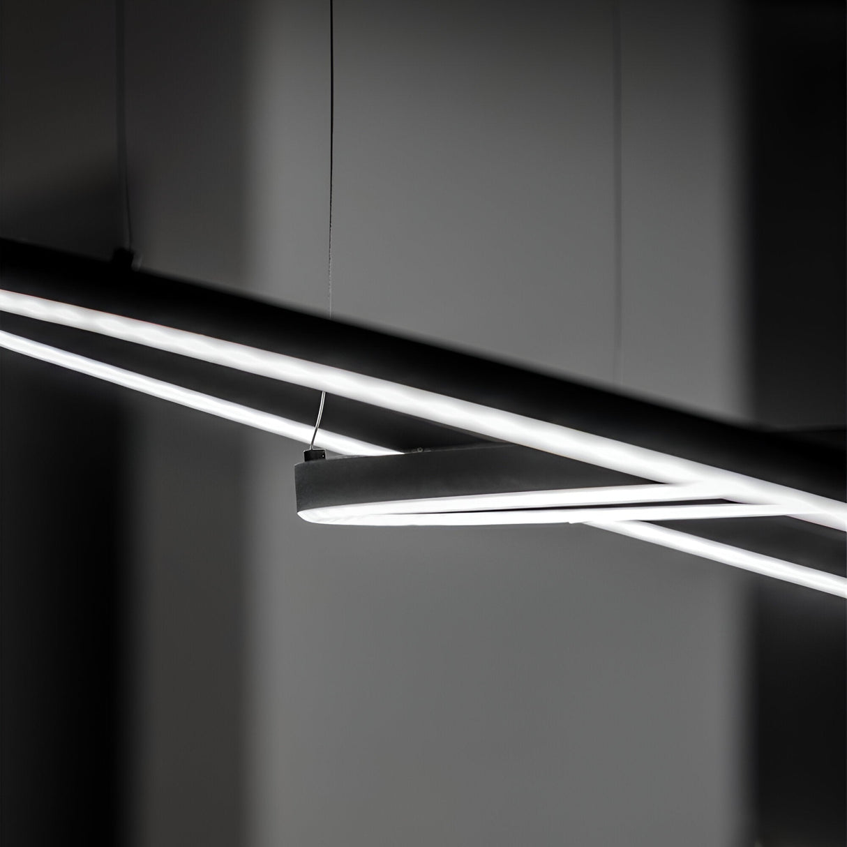 Close-up of the Arcena Round LED Suspension Light showcasing a modern, abstract design with long, slender LED tubes against a dark background. These energy-efficient lights provide an industrial look and create a stark contrast with their glowing white light.