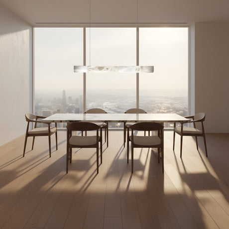 A modern dining room with a large rectangular table, six chairs, wooden floors, and floor-to-ceiling windows showing a city view. Above the table hangs the Zareon LED Small Linear Alabaster Suspension Light – Soft White.