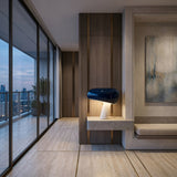 Niori Sleepy Marble Table Lamp with black glossy domed shade and white marble base on a floating console in a modern apartment with city skyline views.