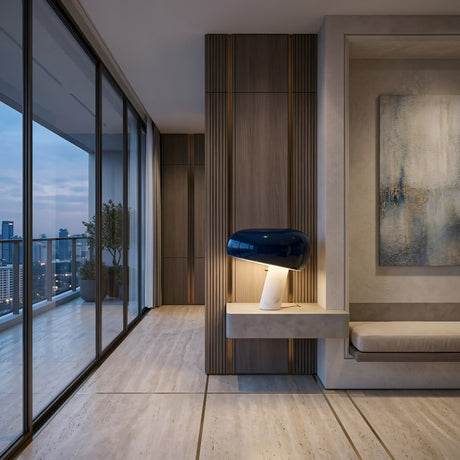 Modern interior with floor-to-ceiling windows overlooking a city skyline, sleek wood and stone finishes, the Sleepy Marble Table Lamp - Black on a floating shelf, blue and white accents, and abstract wall art.