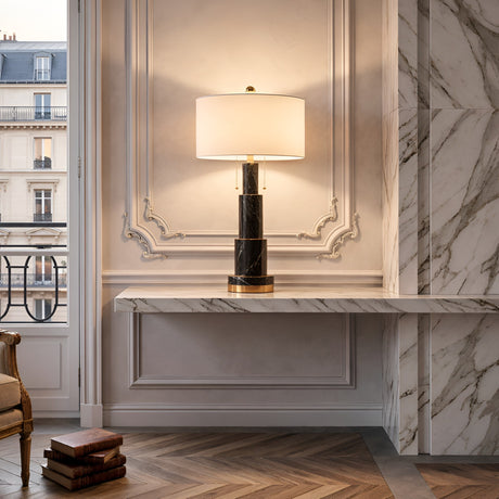 The Eloria 1 Light Stacked Alabaster Table Lamp in soft white and black sits on a marble console table against an ornate wall, with large windows, marble accents, and books completing the elegant interior.