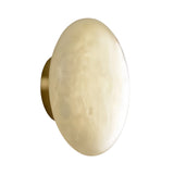 The Solenne LED Large Halo Alabaster Wall Light features a round, wall-mounted design with a smooth, soft white glass shade and a brass base, shown against a white background.