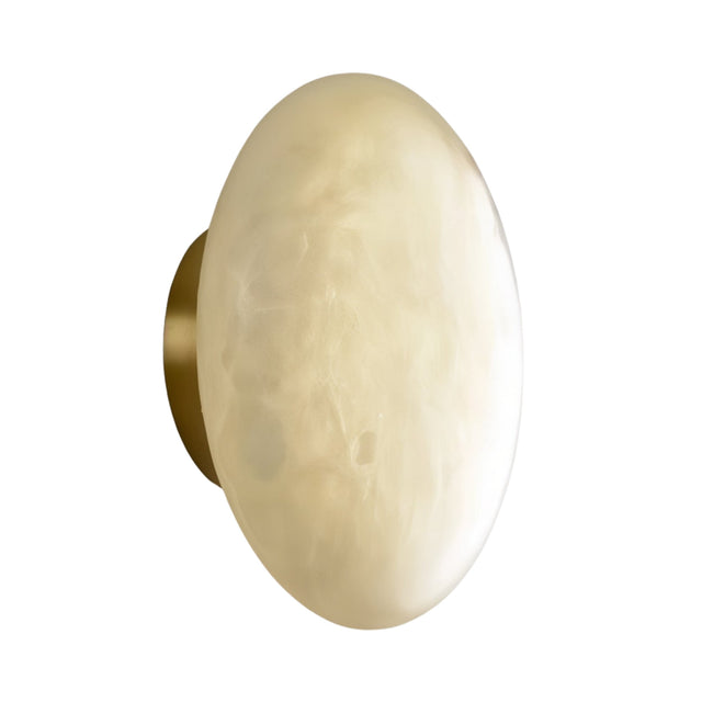 The Solenne LED Large Halo Alabaster Wall Light features a round, wall-mounted design with a smooth, soft white glass shade and a brass base, shown against a white background.