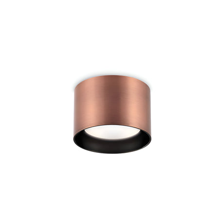 The Orbis Round Downlight - Copper is a ceiling-mounted fixture with a cylindrical, metallic casing and a white light diffuser at its base. Its smooth exterior contrasts with the dark interior, making it perfect for modern interiors. The replaceable LED provides both longevity and adaptability.
